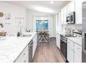 Bright kitchen with white cabinetry, stainless steel appliances, granite countertops, and a view into the dining area at 877 Cypress Creek Run, St Cloud, FL 34771