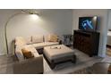 A cozy living room with a wicker sectional, ottoman, and a wall-mounted television at 1100 Martinique Dr # 203, Winter Haven, FL 33884