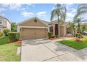 Tan single-story home with a 2-car garage, beautiful landscaping, and a well-maintained lawn at 13852 Eylewood Dr, Winter Garden, FL 34787