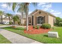 Tan single-story home featuring well-manicured landscaping, green lawns, and a charming front exterior at 13852 Eylewood Dr, Winter Garden, FL 34787
