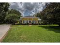 Inviting single-story home featuring a spacious lawn, symmetrical landscaping, and classic columns at 1589 Royal Forest Ct, Lakeland, FL 33811