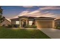 Charming single-story home with a well-manicured lawn and a two-car garage during twilight at 1975 Country Manor St, Bartow, FL 33830