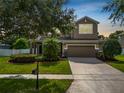 Beautiful home exterior with manicured lawn, mature trees, and a two-car garage beneath a classic architectural design at 228 Magneta Loop, Auburndale, FL 33823