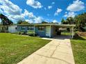 A cozy home with a long driveway, covered carport, and green lawn under a sunny sky at 2655 Hempstead Dr, Lakeland, FL 33801