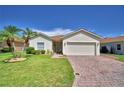 Beautiful one-story home with lush green lawn, palm trees, and brick driveway leading to a two-car garage at 4188 Muirfield Loop, Lake Wales, FL 33859