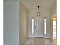 Bright foyer with marble flooring, a modern pendant light, and sidelight windows flanking the entry door at 4188 Muirfield Loop, Lake Wales, FL 33859