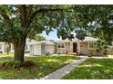 Charming single-story home with neutral siding, green lawn and complemented by mature trees overhead at 819 Glendale St, Lakeland, FL 33803