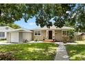 Single-story home features a green lawn, mature tree, and inviting front porch, creating a warm curb appeal at 819 Glendale St, Lakeland, FL 33803