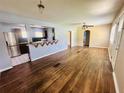 Open-concept living space featuring hardwood floors, ceiling fan, and a pass-through to the kitchen at 938 E Lowell St, Lakeland, FL 33805