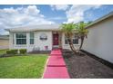 Up close shot of a cozy home with a red door, landscaping, and decorative front yard at 1420 Meadows Pond Dr, Bartow, FL 33830