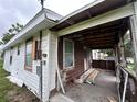 Exterior showing the porch and the damage, along with a cluttered area at 1938 Lavon St, Lakeland, FL 33805
