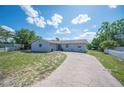 Inviting single-story home with a long driveway, complemented by a white picket fence and mature trees at 1948 Oakland Park Dr, Lake Wales, FL 33898