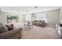 Bright, carpeted living room featuring neutral tones, comfortable seating, and natural light from large windows at 1948 Oakland Park Dr, Lake Wales, FL 33898