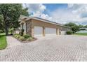Spacious paver driveway leading to a three-car garage with a stone and stucco exterior at 2026 Indian Sky Cir, Lakeland, FL 33813