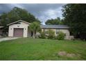 Single story home with attached garage, small palm tree and green lawn at 240 Lake Thomas Dr, Winter Haven, FL 33880