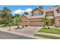 Inviting townhome with a brick driveway, attached garages, and mature palm trees at 6365 Torrington Cir, Lakeland, FL 33811