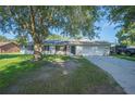 A single-story home with a brick facade, an attached garage, and mature trees in the front yard at 6507 Shadowbrook Run, Lakeland, FL 33813
