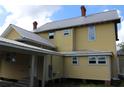 Rear exterior view of a two-story yellow home with a metal roof at 701 1St Ne St, Fort Meade, FL 33841