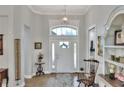 Elegant foyer with a decorative front door, transom window, and an ornate light fixture, complemented by hardwood floors at 7770 Lake James Blvd, Lakeland, FL 33810
