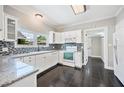 Well-lit kitchen with white cabinets, dark tile floor, granite countertops, and stainless-steel appliances at 783 E Central Ave, Eagle Lake, FL 33839
