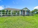 Front exterior view of a well-maintained home with a white fence, green lawn, and mature trees at 15195 Angus Rd, Polk City, FL 33868