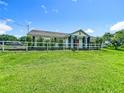 Exterior of home with a well-manicured lawn, white fence, and elegant columns, creating a welcoming atmosphere at 15195 Angus Rd, Polk City, FL 33868