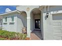 Covered entranceway with decorative arch and well-lit front door to charming single-story home at 2169 Rush Bay Way, Orlando, FL 32824