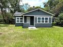 Close exterior view of renovated home with gray paint, white trim, and manicured front lawn at 6127 Crews Lake Rd, Lakeland, FL 33812