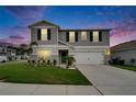 Charming two-story home at dusk with manicured lawn, gray siding, dark green shutters, and an attached two-car garage at 7116 Cruz Ct, Lakeland, FL 33813
