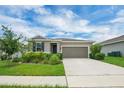 Charming single-story home featuring a well-manicured lawn, front garden and a two-car garage at 221 Hilltop Bloom Loop, Haines City, FL 33844
