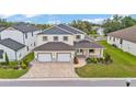 Aerial view of a two-story home featuring a three-car garage, a brick-paved driveway, and well-maintained landscaping at 2736 Sunrise Landing Ln, Lakeland, FL 33812