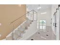 Bright foyer boasts soaring ceilings, a modern staircase with glass railings, and elegant tile flooring at 2736 Sunrise Landing Ln, Lakeland, FL 33812