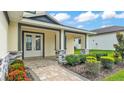 Charming covered front porch with brick accents, stylish double front doors, and manicured landscaping at 2736 Sunrise Landing Ln, Lakeland, FL 33812