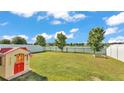 Lush backyard featuring a playhouse, green grass, black metal fence, and serene lake views for Gathering enjoyment at 3739 Peregrine Way, Lakeland, FL 33811