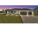 Beautiful home at dusk with a well-manicured lawn, three-car garage, and stylish black and white exterior at 6707 Hillis Dr, Lakeland, FL 33813
