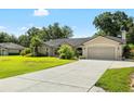 Well-maintained single-story home with a long driveway and attached garage, surrounded by lush green lawn and mature landscaping at 2208 Deerbrook Dr, Lakeland, FL 33811