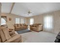 Cozy living room with neutral walls, carpet, ceiling fan, and multiple seating options at 6443 Hollyberry Ne Ln, Winter Haven, FL 33881