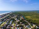 Expansive aerial view of a coastal community with a mix of homes, wetlands, and the ocean at 4606 Doris Dr, New Smyrna Beach, FL 32169