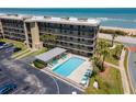 Aerial view of the condo complex showcasing a refreshing pool area near the ocean at 3180 Ocean Shore Blvd # 208, Ormond Beach, FL 32176