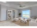 Bright living room featuring tile flooring, a ceiling fan, sliding glass doors with ocean views, and coastal decor at 3180 Ocean Shore Blvd # 208, Ormond Beach, FL 32176