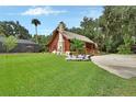 Log cabin on expansive lawn with a stone chimney, covered porch, and beautiful landscaping at 2536 Paige Ave, New Smyrna Beach, FL 32168