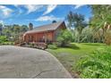 Rustic log cabin with an inviting porch, lush greenery, and a spacious driveway at 2536 Paige Ave, New Smyrna Beach, FL 32168