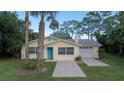 Charming yellow single-story home with a vibrant turquoise front door and an attached one car garage at 1949 Bayview Dr, New Smyrna Beach, FL 32168