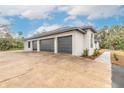 Three-car garage with dark gray doors and a long driveway at 1371 Melonie Trl, New Smyrna Beach, FL 32168