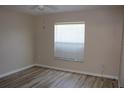 Cozy bedroom with wood-look flooring, a ceiling fan, and a bright window with blinds at 537 Coral Trace Blvd, Edgewater, FL 32132