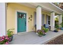 Bright teal front door and gray porch with potted plants at 915 Maple St, New Smyrna Beach, FL 32169