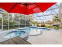Inviting screened-in pool with hot tub, red umbrella, and lounge chairs, ideal for outdoor enjoyment at 1052 Tompkins Dr, Port Orange, FL 32129
