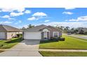 Exterior view of a house showcasing a two-car garage and a spacious front yard at 230 Oak Branch Dr, Edgewater, FL 32141