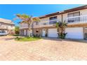 Multi-Gathering building with white balconies over garages, surrounded by lush landscaping and a patterned brick driveway at 731 Laurel Bay Cir, New Smyrna Beach, FL 32169