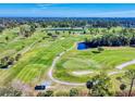 Aerial view of a golf course with lush green fairways and a pond at 103 Sea St, New Smyrna Beach, FL 32168